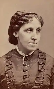 A hazy photogragh of Louisa May Alcott, with dark hair wearing a dress