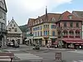 View to a street: Place du Marché-rue Saint-Gregoire-Grand Rue with townhall