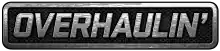 A simple logo spelling the word "Overhaulin' " in block capital letters in silver over what appears to be a car grill or interlaced gray mesh