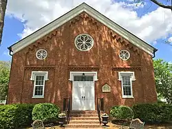 A red brick church building featuring white double doors
