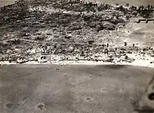 Aerial view of Betio, Tarawa Atoll, 24 November 1943, looking north toward "The Pocket", the last place of Japanese resistance. An emplacement just onshore with two 12.7&nbsp;mm anti-aircraft guns is visible near the left edge of the photograph.