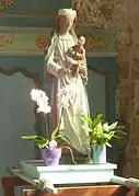 Statue  de bois peint : femme en longue robe blanche revêtue d'une cape bleue, tenant un enfant assis sur son bras.