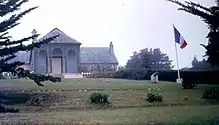 Un perron de cinq marches relie la véranda de treillage (sans vitres désormais) au gazon pelé et à la pièce principale de l'aile centrale