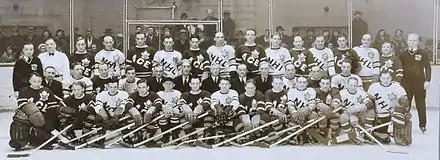 Photographie en noir et blanc de deux équipes de joueurs de hockey sur glace équipés et en train de poser sur la glace en tenue.