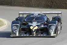Photographie d'une voiture de sport-prototype verte et grise, vue de face, sur une piste.