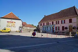 Un bâtiment ancien à grand toit, au fond d'une petite place.