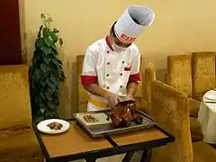 Découpage du canard devant les clients d'un restaurant gastronomique de Pékin.