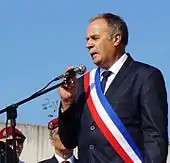 Portrait rapproché d'un homme portant une écharpe tricolore.