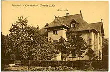 Carte postale d'une villa bourgeoise, à la façade claire, assez opulente, mais sobre, avec plusieurs pas de toits en tuiles, et entourée d'une haie, vue depuis un jardin.