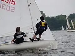 Équipier au trapèze sur 420 (mauvaise  position des pieds dont les talons sont sur le liston).