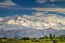 Des montagnes aux sommets dans les nuages mais avec des pentes enneigées avec une belle luminosité.