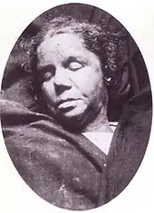 Photographie mortuaire en noir et blanc du visage d'une femme dans la quarantaine aux lèvres charnues.