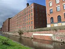 Photoraphie. Manufactures en brique« La masse rectangulaire de grandes usines aux multiples fenêtres… » Ancoats'Mills (Murray's Mills aujourd'huiMrs Gaskell amenait ses visiteurs aux Murray's Mills (dans le quartier d'Ancoats, le long du Canal Rochdale), pour leur montrer tout le processus de la fabrication des cotonnades.).