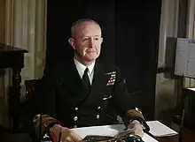 Photo d'un homme assis à un bureau, portant un uniforme d'officier de la marine
