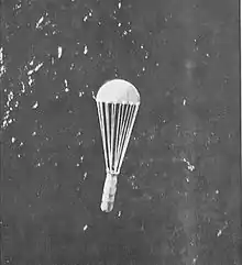 Un cylindre métallique suspendu à un parachute est largué au-dessus de l'eau.