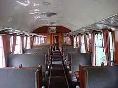 Voiture à couloir central de troisième classe en configuration plus luxueuse (2+1 places).
