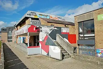 Le porche d'entrée en béton situé au sud, orné de peintures murales de Fredone Fone.