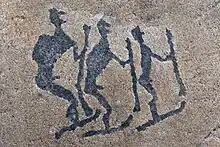 Pétroglyphes de trois personnes sur une roche.