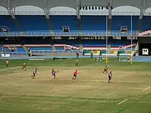 Un joueur de rugby frappe au pied dans le ballon, d'autres courent dans la même direction que le ballon.