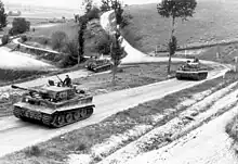Photo montrant trois blindés allemands sur une route de campagne.