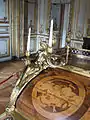 Bronze masculin et détail de la partie gauche de l'abattant avec une marqueterie illustrant la Poésie dramatique reprenant la mention latine NON NISI GRANDIA CANTO  — IRRINDENS CUSPIDE FIGO,  tirés de l'Iconologia de Cesare Ripa (« Je ne chante rien que des choses assez grandes - Moqueuse, je transperce de ma lance »).