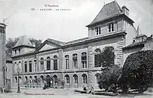 Phototyoie d'un bâtiment de deux étages du début du XXe&nbsp;siècle. Au centre fronton au-dessus de deux fenêtres, deux ailes de trois fenêtres et à chaque extrémité surélévation d'un étage au-dessus d'un corps de bâtiment à deux fenêtres.