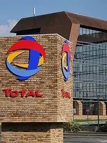 Photo d'un bâtiment en brique et en verre, au premier plan le nom de l'entreprise.