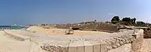 Photographie d'un amphithéâtre en ruine au bord de la mer.