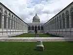 Vaste cloitre. Murs percés fines arcatures gothiques, pelouse centrale. Au fond, un dome