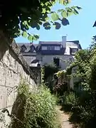 Photographie en couleurs d'une maison à étages au fond d'une ruelle.