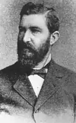 Portrait noir et blanc d'un homme en civil portant la barbe.