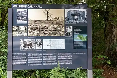 Panneau explicatif pour les visiteurs (2019) qui présentent diverses photos. Dans le sens des aiguilles d'une montre : 1. Vue de 1934, depuis le Wuckersee&nbsp;(de), montrant la Carinhall initiale ; 2. Photo de 1940 avec les travaux en cours pour la seconde extension ; 3. Un passant devant les ruines en 1947 ; 4. Portrait de Göring (1932) en uniforme SA ; 5. Plan de la bande de terre entre les deux lacs, avec la mention des deux extensions de Carinhall (1937 et 1940), Göring avait planifié la fin de la troisième extension (concernant un nouveau musée) pour 1953 ; 6. Plan du projet de cette troisième extension tel que présenté le 12 janvier 1945 ; 7. Visite du général japonais Oshima en mars 1940 ; 8. Göring reçoit le ministre des Affaires étrangères britannique, Lord Halifax, le 20 novembre 1937 ; 9. Le 19 juin 1934, Göring, accompagné de Hitler, sort de la crypte aménagée pour sa défunte épouse Carin, sur la rive nord du Wuckersee&nbsp;(de).