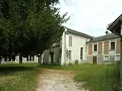 Photographie en couleurs d'un bâtiment aux baies en plein cintre imbriqué dans d'autres constructions.