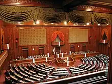 Salle de grande taille à la décoration opulente de bois sculpté. Une longue tribune avec deux rangées de bureaux occupe le mur du fond avec un imposant bureau au centre, une table pour quatre greffiers se trouvant à son pied, les bureaux et sièges des représentants formant un hémicycle devant la tribune.