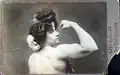 Carte postale promotionnelle montrant Charmion de trois-quart dos, le dos dénudé et le bras droit plié pour mettre en valeur son épaule et son biceps ; elle regarde vers l'objectif et le spectateur