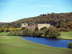 Photo. Château avec rivière, larges pelouses et colline boisée