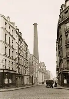 Ancienne photo avec une cheminée en briques de la raffinerie Say.