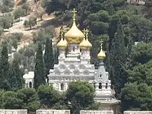 photographie couleurs : une église à bulbes dorés dans la végétation.