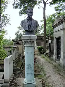 La colonne de la tombe de la famille Robinet. Le chapiteau est du style art-déco, et surplombé par un petit bonnet phrygien. En haut de colonne, un buste de François-Roland Rolard, vêtu d'un costume. Il possède une cravate en lavallière, une moustache et une petite barbe sur le menton ainsi que des cheveux courts. Six noms sont inscrits sur la colonne, trois sont illisibles. Les autres sont : « Gabriel Robinet, 15 mars 1849 - 26 juillet 1887. Docteur Robinet, exécuteur testamentaire d'Auguste Comte, historien de Danton, 24 avril 1825 - 2 novembre 1899. L. Gabriel-Robinet, membre de l'Institut, 1909 - 1975. » La devise positiviste est aussi gravée sur la colonne : « L'amour pour principe, l'ordre pour base et le progrès pour but » ; sur son socle il est écrit « Concession à perpétuité. »