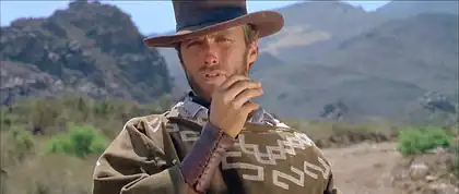 Homme portant un chapeau et tenant un cigare.