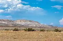 Une plaine agricole, à l'arrière-plan de grandes falaises roses.