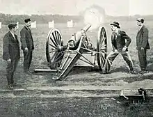 Photo de quatre hommes autour d'un canon dont la bouche crache des flammes.