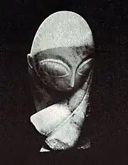 Tête sculptée toute en courbes avec torsion du cou, nez pointu, yeux vides immenses
