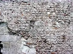 Photographie en couleurs d'un mur dont certaines pierres dessinent des chevrons.