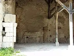 Photographie en couleurs d'un ancien mur formant le fond d'un hangar couvert.