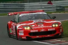 Une voiture rouge, blanche et verte, vue de face, sur une piste.