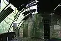 Intérieur de la cabane abandonnée de Nissen ; les tôles ondulées formant les murs et le toit sont soutenues par des cloisons de séparation en briques et des poutres métalliques.