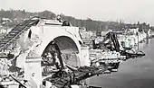 Photographie en noir et blanc d'un pont détruit.