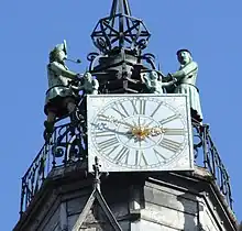 Vue en contre plongée, d'une horloge au sommet d'un campanile, avec deux statues de chaque côté
