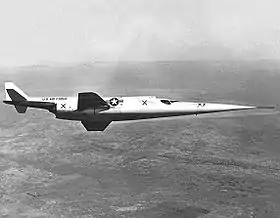 Photographie en noir et blanc d'un avion en vol.